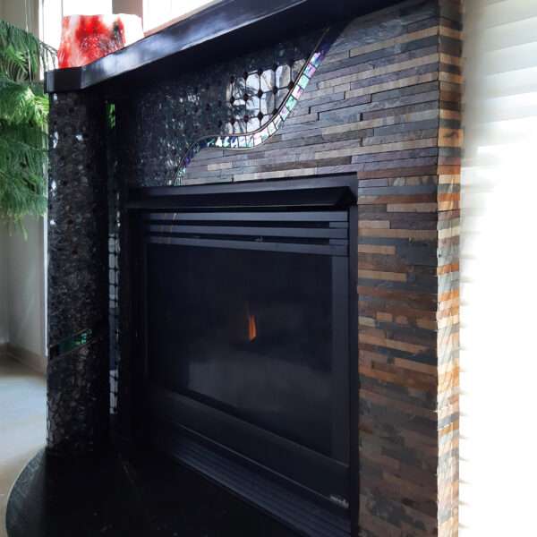 view of fireplace surround from right; horizontal strips of brownish slate; black mantel and apron, freestanding column on left